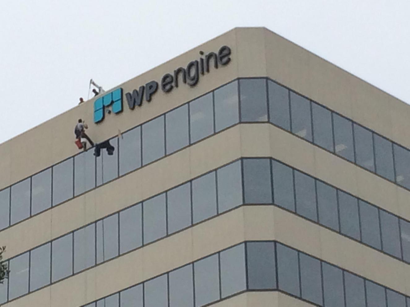 Worker assembles sign on the side of a building